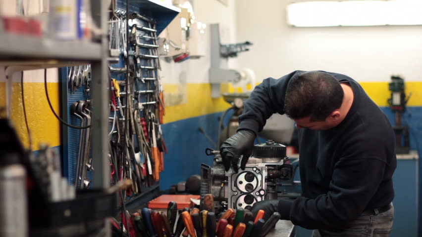 auto mechanic repairing a part of a car engine