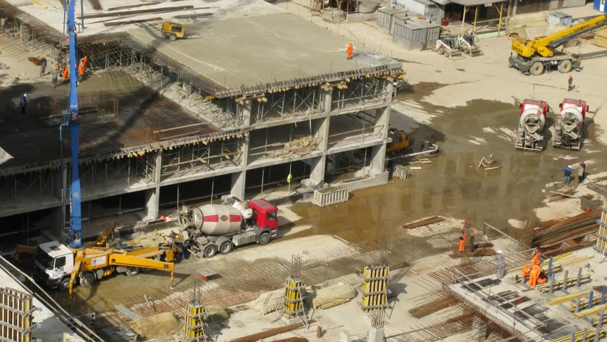 construction workers pour concrete using concrete pump 