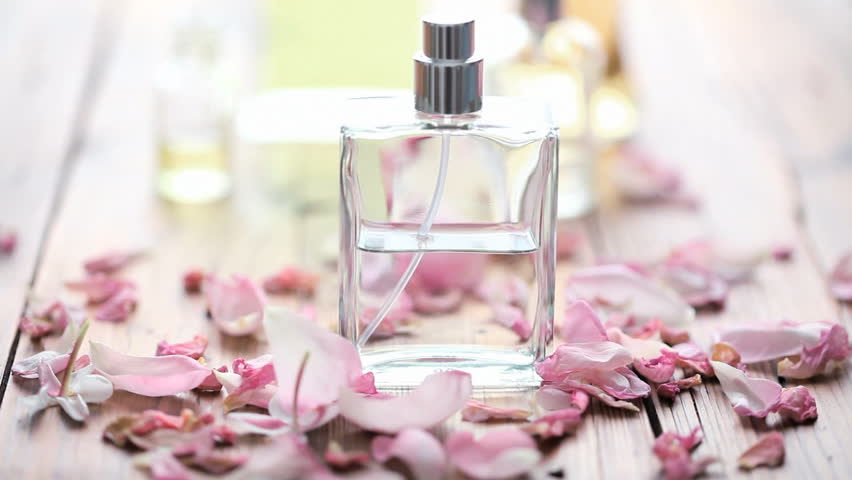 rose petals blown away from perfume bottle 