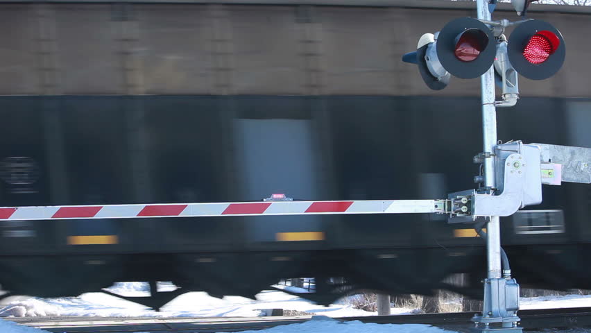 Railroad coal cars passing at road crossing. Guard flashing with alarm. Guard raises to open road.