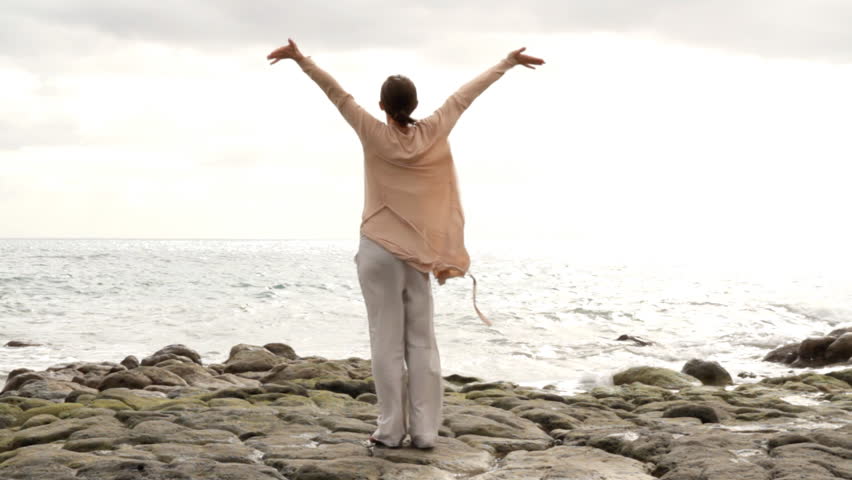 Woman at the beach with arms wide open 