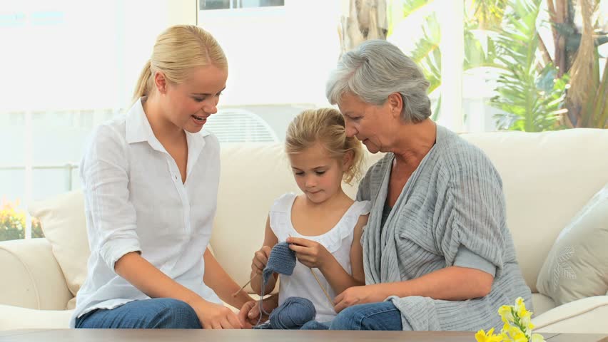 Girl knitting with her mother and Grandmother on the sofa