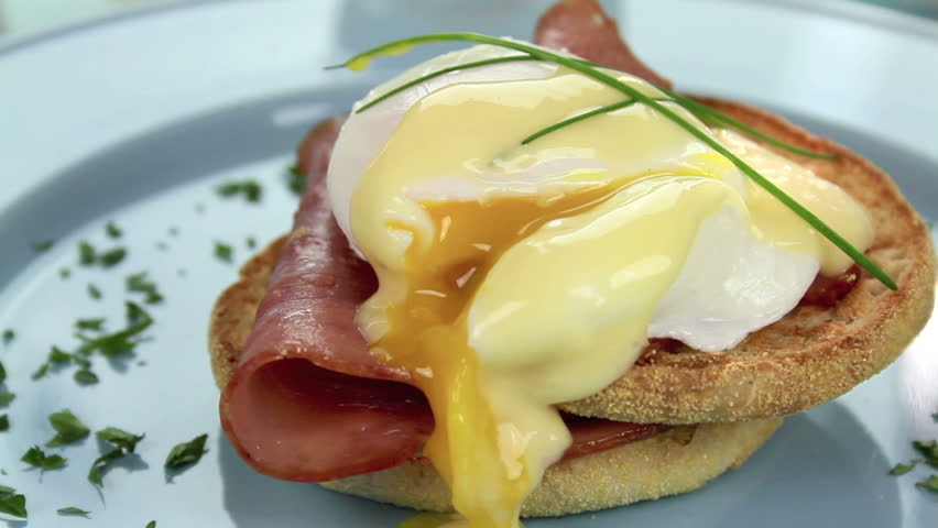Oozing egg and ham benedict garnished with chives and parsley