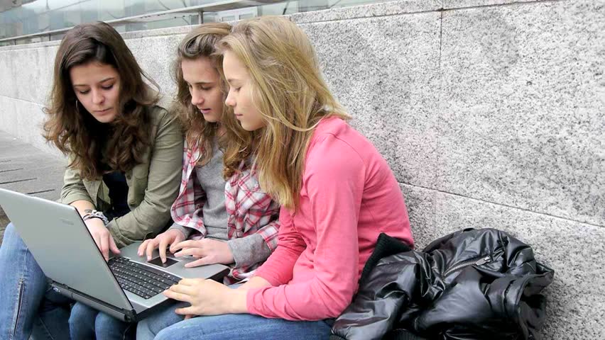 Teenage girls with laptop computer in school yard