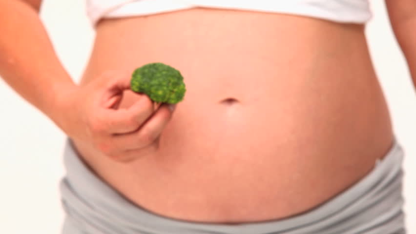 Pregnant woman holding a cabbage against a white background