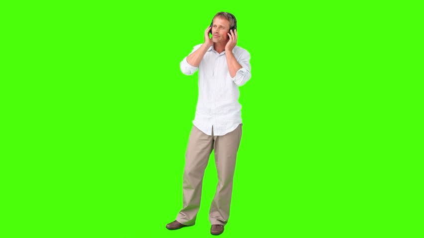 Chromakey footage of a casual man in shirt listening to music with headphones