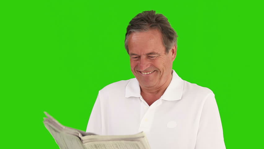 Retired man reading a pleasant article in the newspaper against a green screen