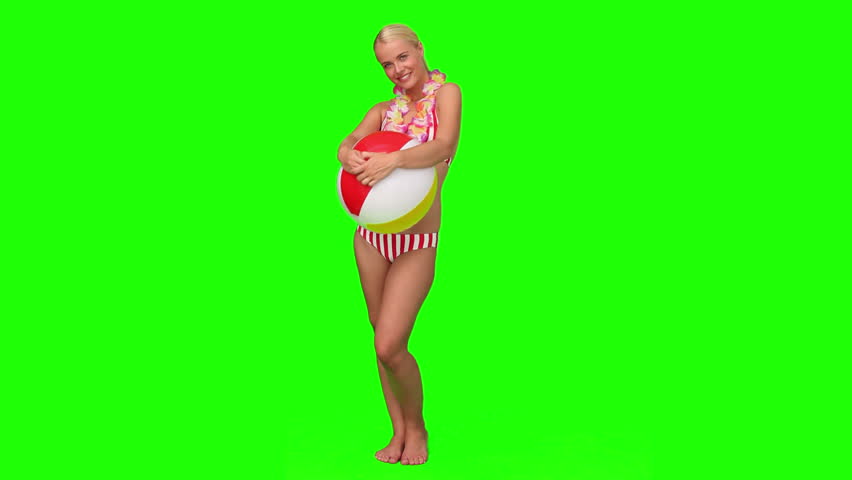 Chromakey footage of a blond woman on vacation holding a ball