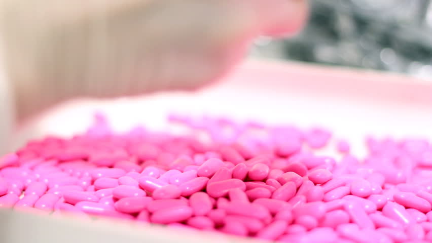 Technicians inspecting the quality of pills at a pharmaceutical plant.