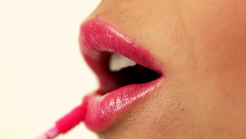 Woman applying pink lip gloss, close up
