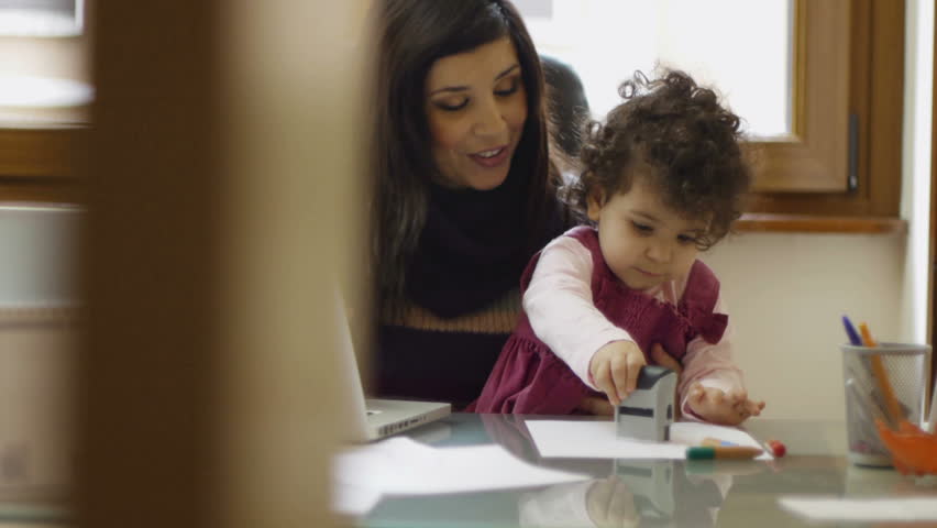 Mom and businesswoman working with laptop computer at home and playing with her baby girl. Dolly shot