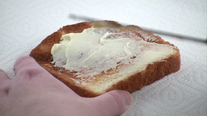 Buttering a piece of white toast.