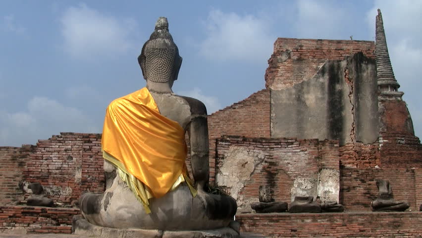 Back of a stone Buddha with yellow drape  at Wat Mahathat in Ayuthaya in Thailand 