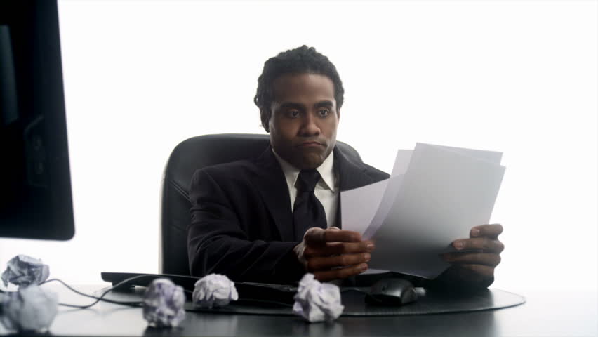 An African man  crumples notes in his office 
