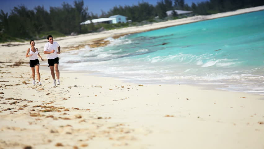 Attractive caucasian couple jogging along a beautiful island coastline