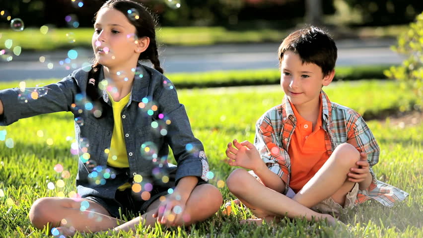 Two caucasian children in their garden laughing at play bubbles