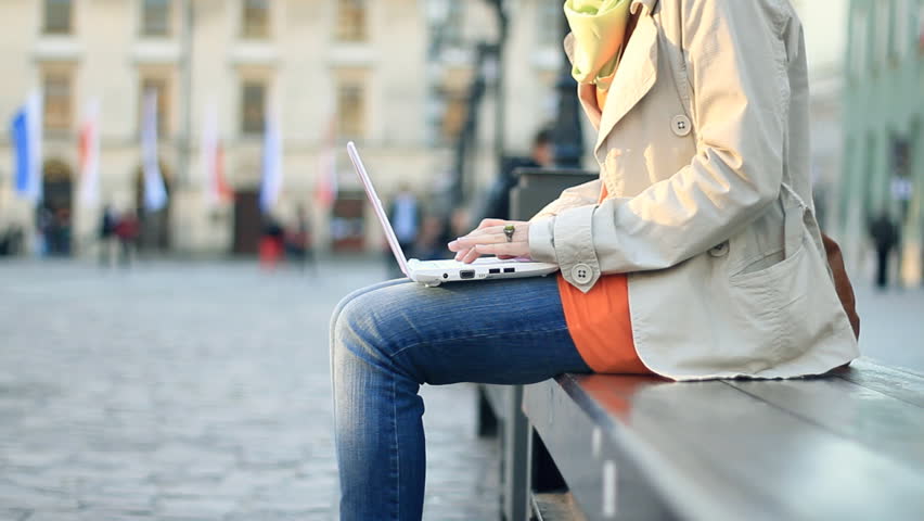 Woman with laptop sitting in urban environment, camera stabilizer shot