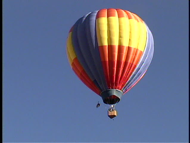 Zoom in on a brightly colored single balloon against a blue sky in the Albuquerque Balloon Festival
