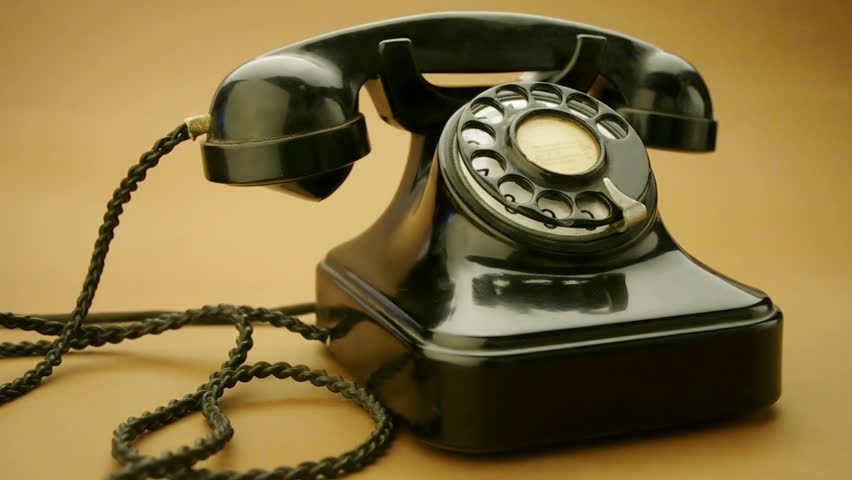 male hand on very old telephone on brown background