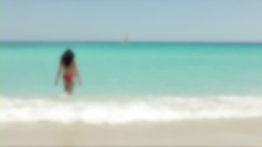 beautiful latina brunette walking on tropical beach with red bikini