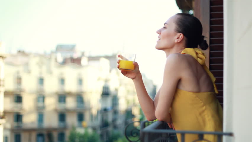 Woman drinking orange juice on the balcony