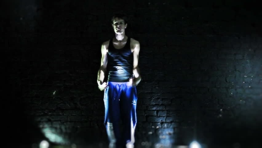 Young man dancing on wall background. 
