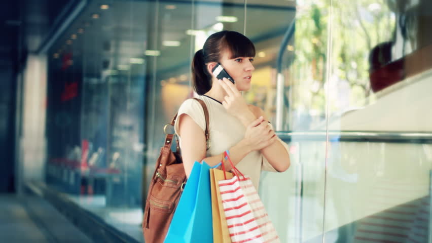 Woman talking on mobile phone and looking at shop window 