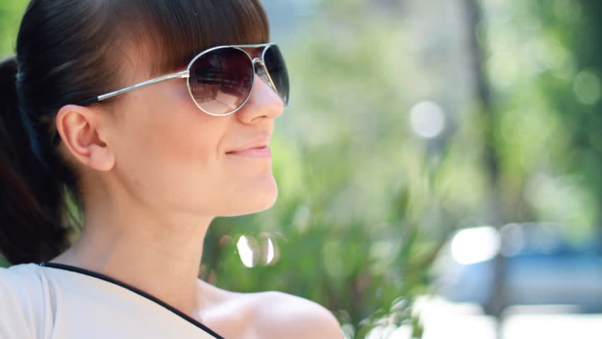 Attractive woman taking off sunglasses and smiling to camera 