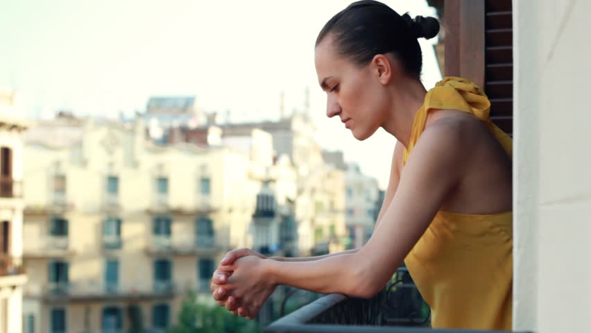 Young sad woman standing on the balcony