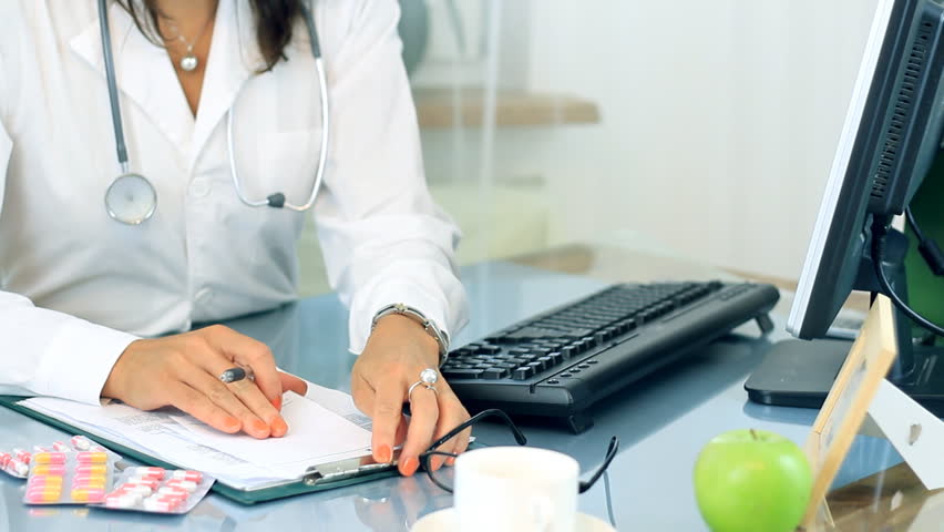 Female doctor looking at medications and writing rx prescription