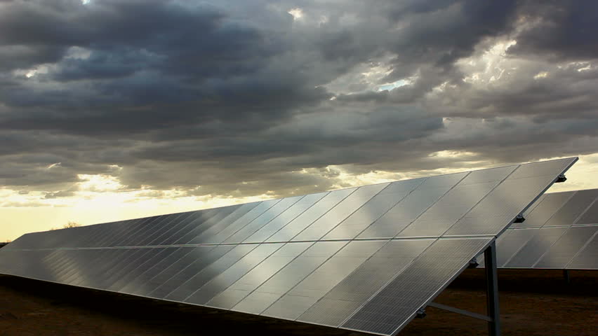 Time Lapse, Sun seeps through thick cloud layer, sweeps across photovoltaic panels in late afternoon. 1080p