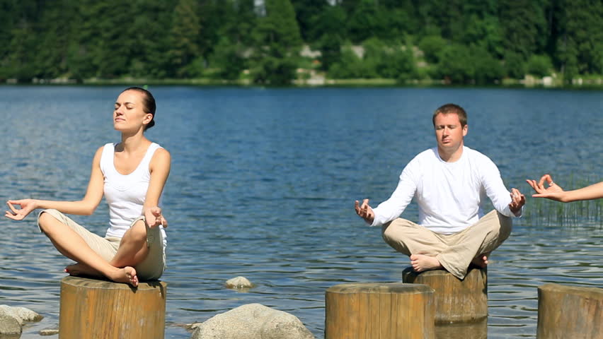 Group of meditating people by the lake, dolly shot