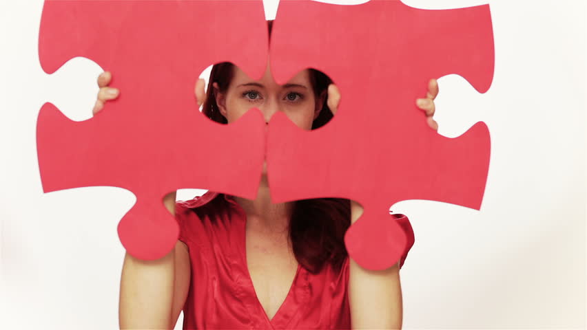 Happy woman showing two oversized jigsaw puzzle pieces