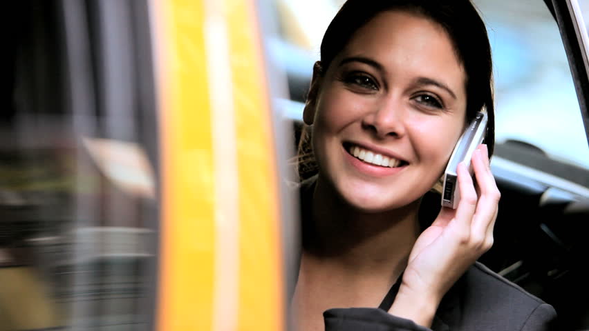 Close-up of smart young female in the back of a city cab talking on a cell phone