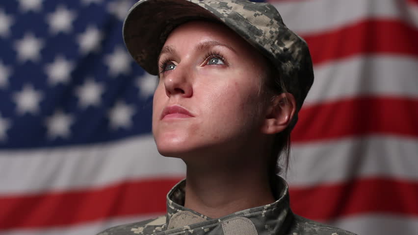 Female soldier in front of US flag, looking up