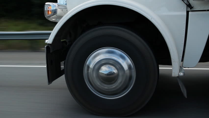 Truck wheel with reflection. Closeup of a truck wheel on the highway. Reflection of car in truck hubcap. 
