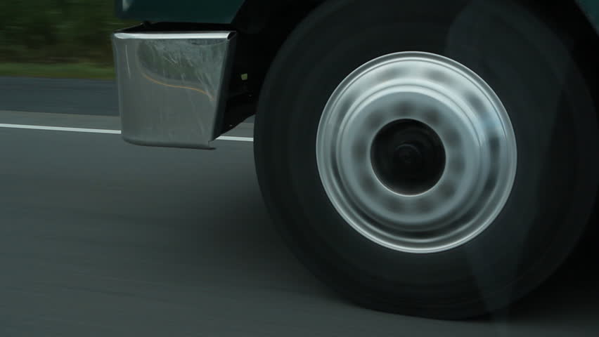 Truck wheel. Closeup of a truck wheel on the highway. Reflection in passenger window. 