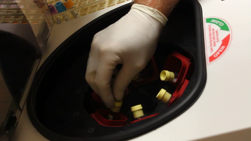 Medical lab technician loads centrifuge, locks it, switches it on. 1080p