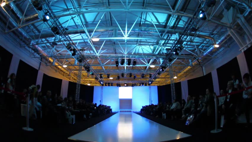Many people are waiting for next fashion show, sitting in dark 