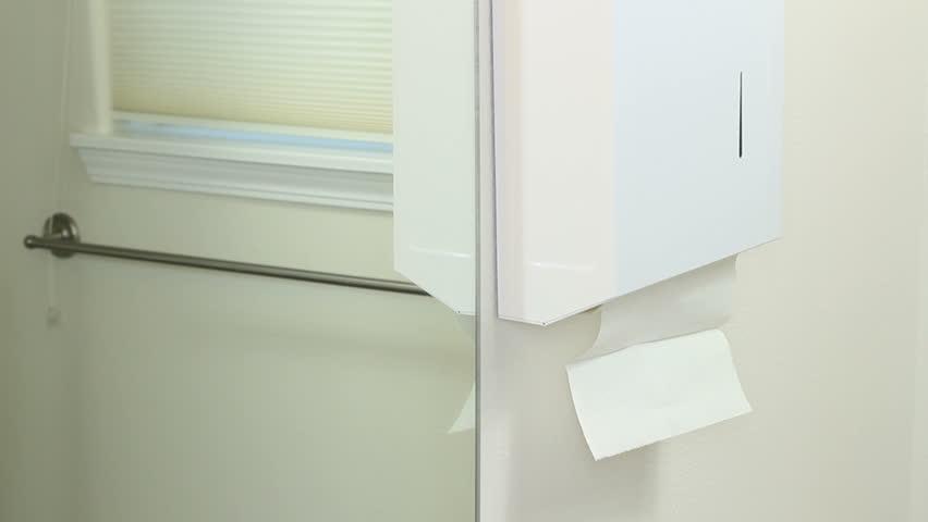 Man drying hands with paper towels in a bathroom.