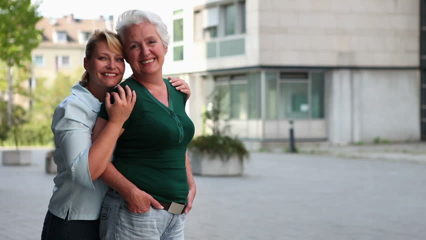 Two senior women in a city holding thumbs up