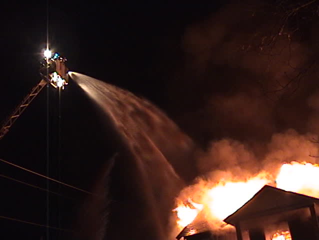 Ladder truck flowing water on a structure fire.