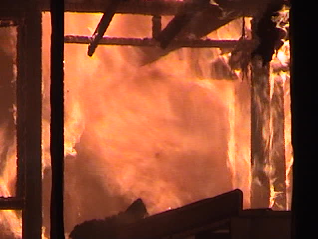 Fire engulfs the inside of a structure with falling debris.