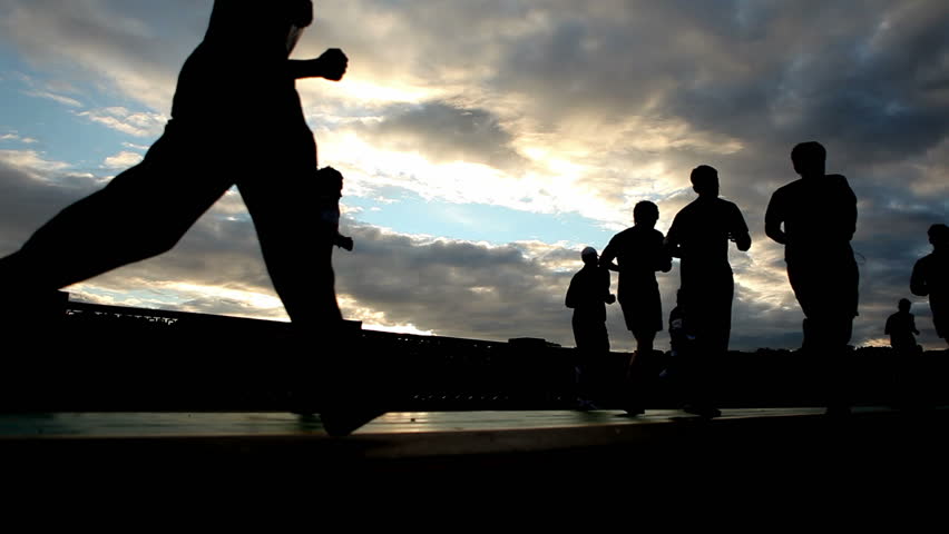 silhouettes of  running people on the background of the sunset sky