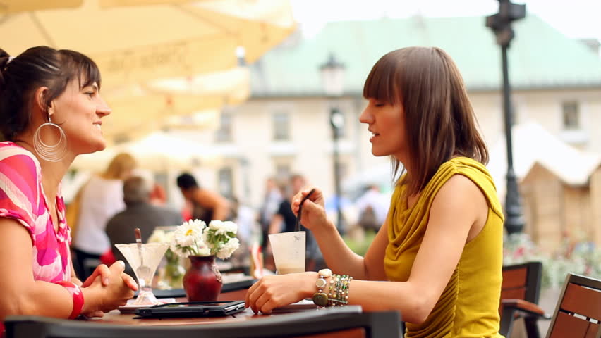 Two female friends chatting in restaurant, outdoors, camera stabilizer shot