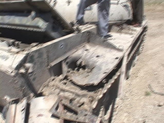 IRAQ - CIRCA 2003: Iraqi men and boys sit on a destroyed tank during the Iraq War circa 2003 in Iraq.