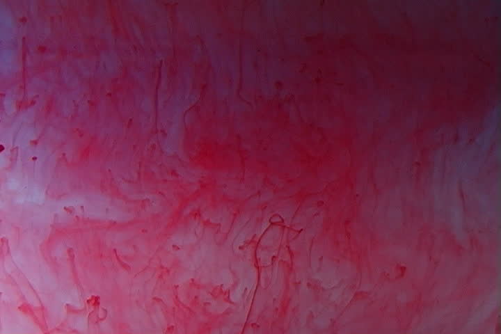 Red ink elegantly flowing in a liquified chamber.
