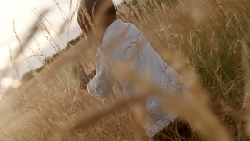 A father and son play in a wheat field on a sunny day.