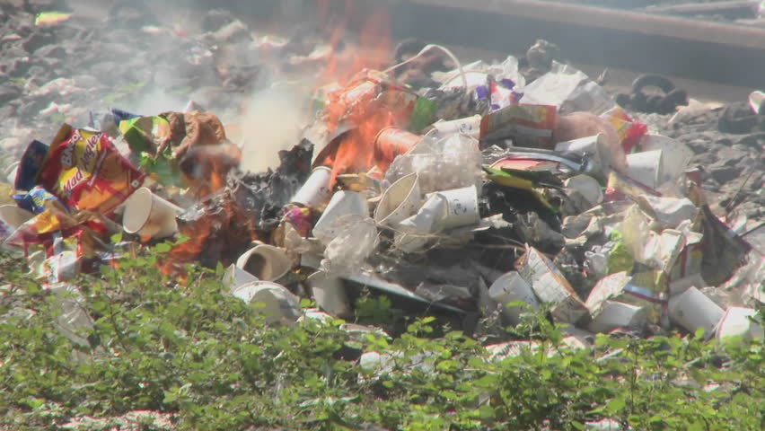 Burning rubbish piles close by railroad tracks