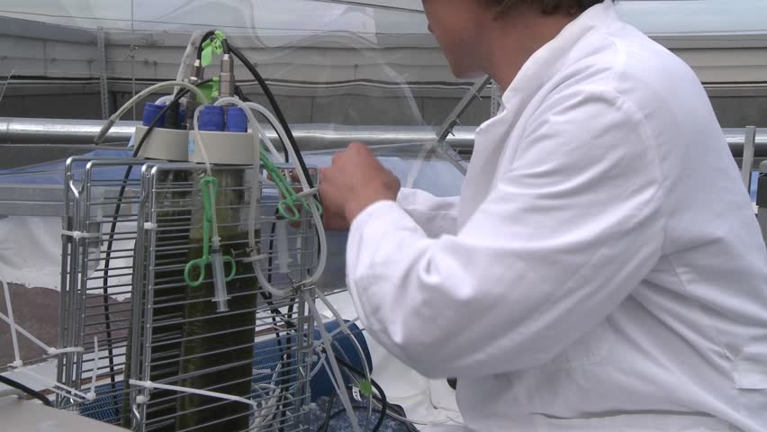 Dolly moving from one scientist working with a flat panel towards other flasks where we discover another scientist in the background.